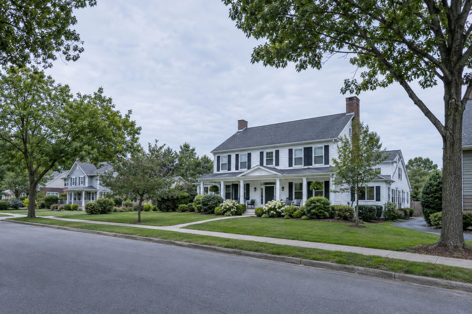 Large white colonial house used as a residential care home on a tree-lined street